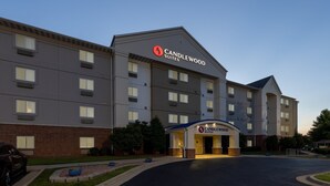 Un hôtel à plusieurs étages, reconnaissable à son grand panneau « Candlewood Suites », doté d’un parking et d’un espace d’entrée aménagé.