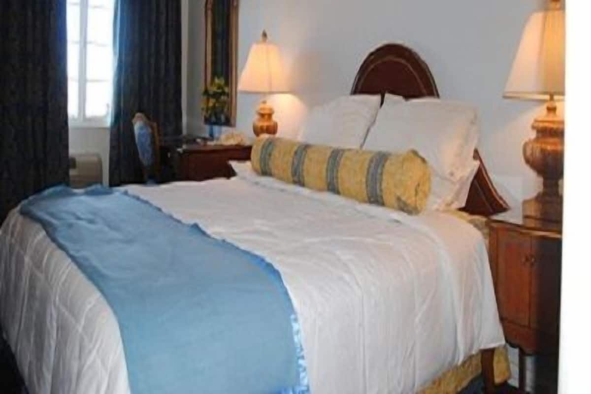 A neatly made bed with a blue and white bedspread, two bedside lamps, and a wooden headboard.