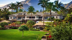 Een resort met een groot gebouw, palmbomen en een berg op de achtergrond.