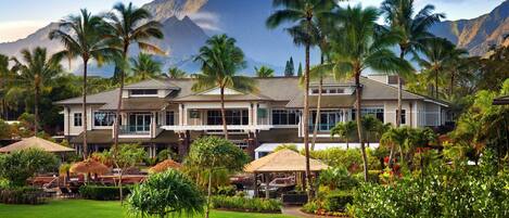 A resort with a large building, palm trees, and a mountain backdrop.