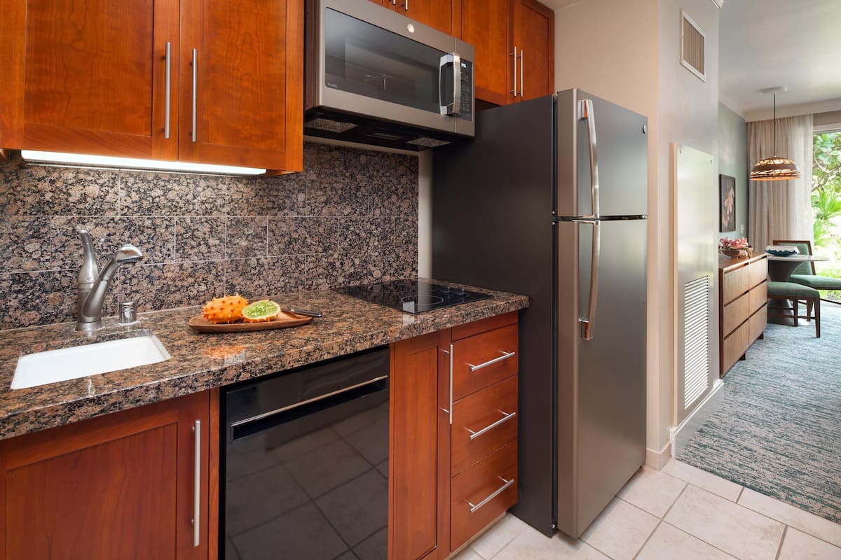 Una cocina con encimeras de granito, electrodomésticos de acero inoxidable, armarios de madera y vistas al exterior.