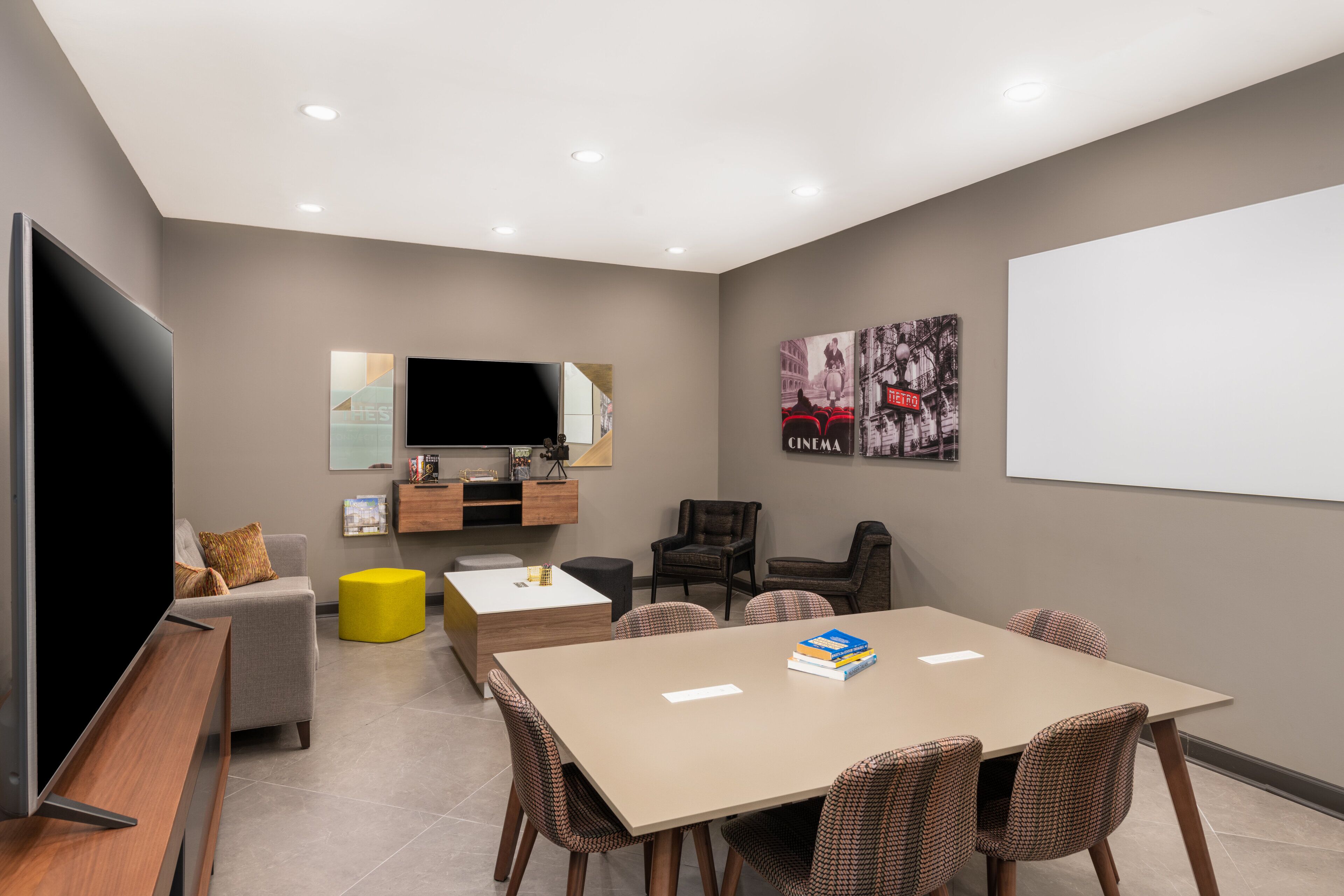 A modern living room with a flat-screen TV, a sofa, a coffee table, and a dining area with a table and chairs.