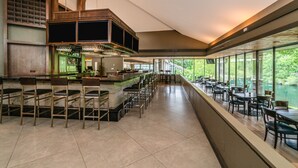 A spacious restaurant with a bar area, high ceilings, and large windows offering views of the outdoors. - Crowne Plaza Atlanta SW - Peachtree City by IHG (Peachtree City)