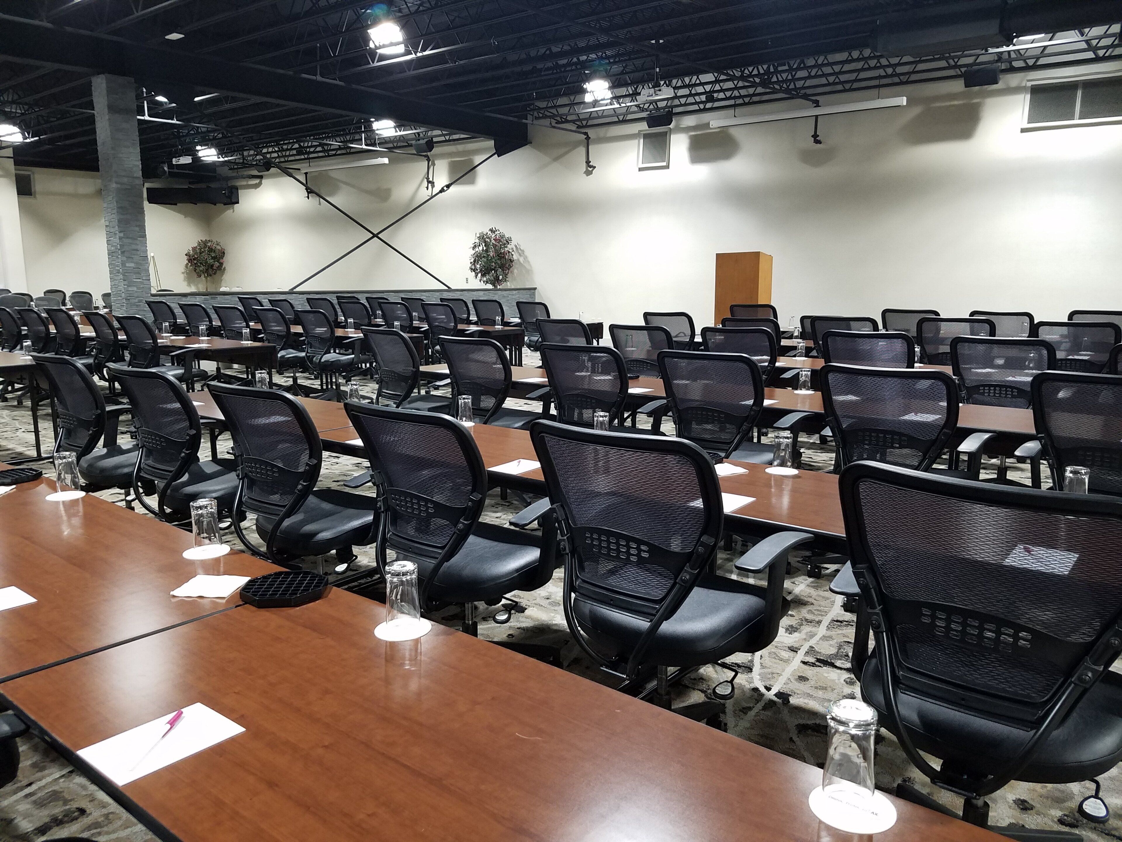 A conference room with rows of tables and chairs, equipped with water bottles and nameplates.