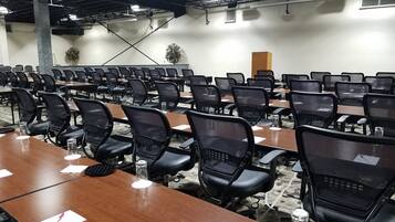 A conference room with rows of tables and chairs, equipped with water bottles and nameplates.