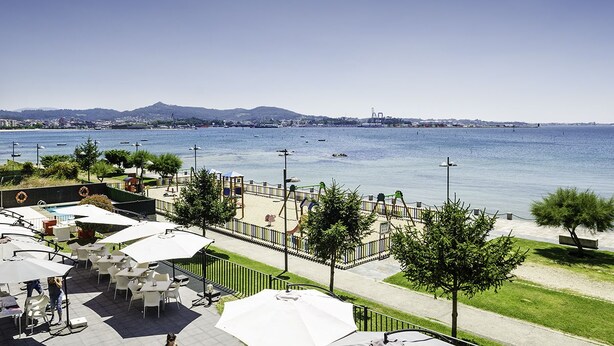 A waterfront patio with outdoor seating and a view of the sea. - Hotel Carril (Vilagarcia de Arousa)