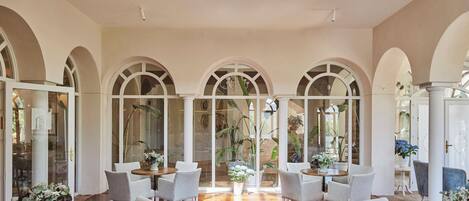 A spacious interior with a high ceiling, arched windows, and a central open area with seating.