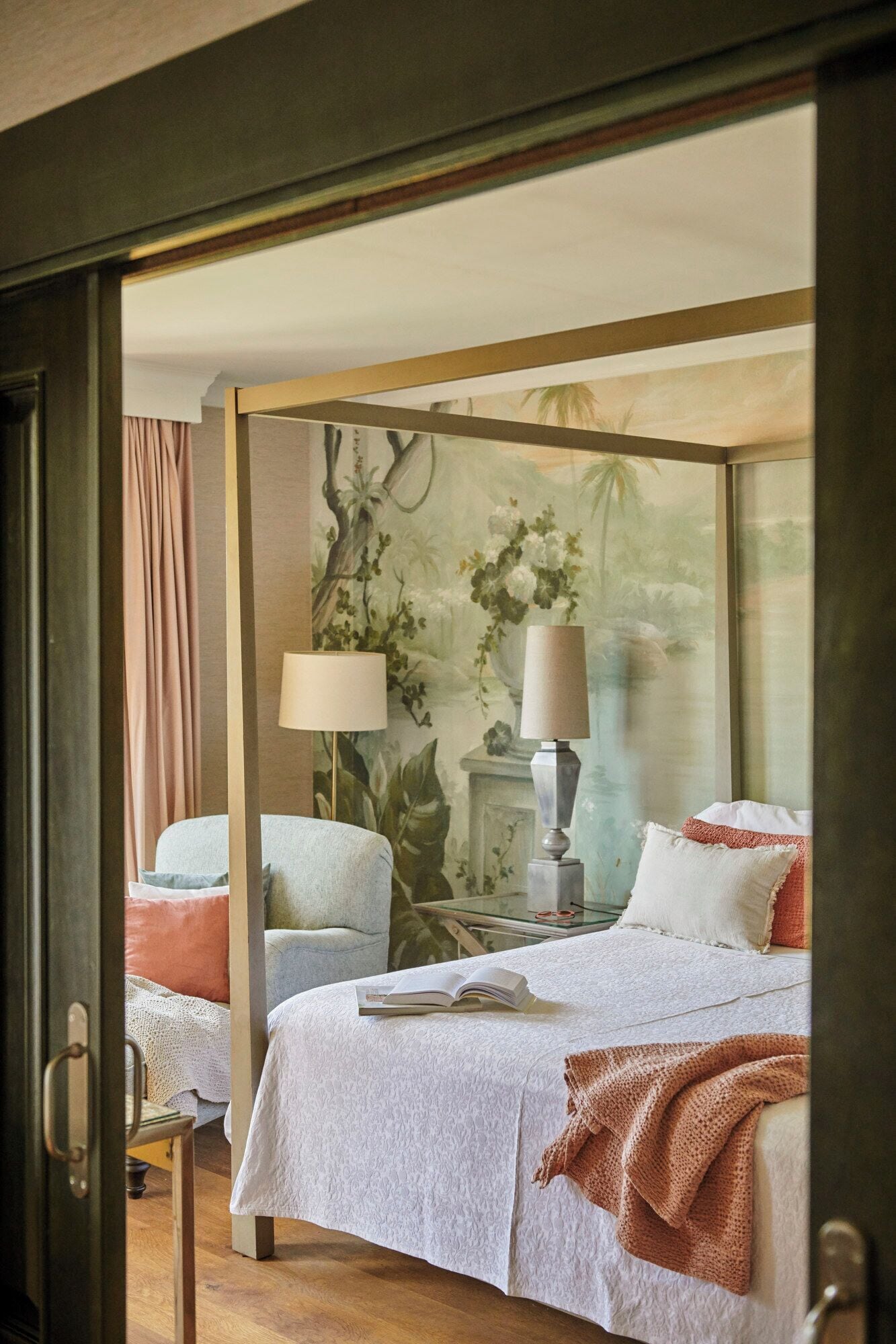 A bedroom with a large bed, a smaller bed, a chair, a lamp, and a bookshelf.