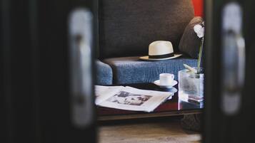 Une pièce chaleureuse avec un mur d’accent rouge, un canapé gris, un chapeau blanc et une petite table sur laquelle se trouvent une tasse et un vase.