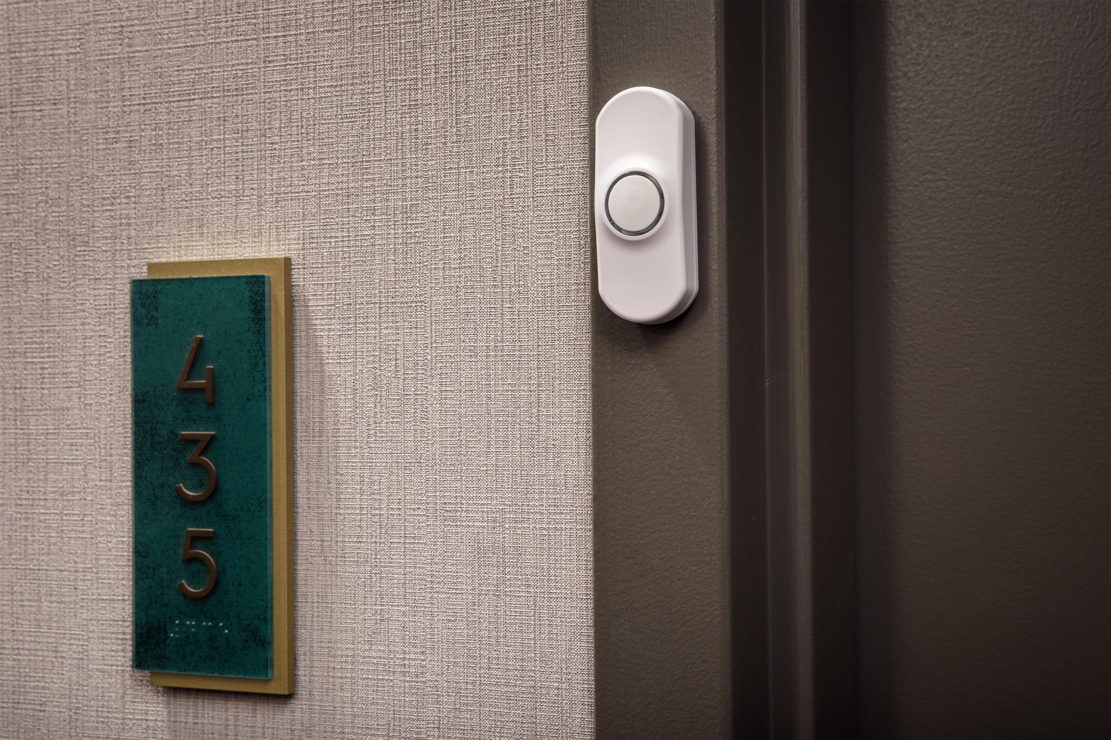 Une porte avec une plaque portant un numéro et un bouton de sonnette.