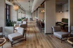 A modern office space with a long dining table, multiple chairs, and hanging pendant lights. - The Clara Hotel Plano Tapestry Collection by Hilton (Plano)