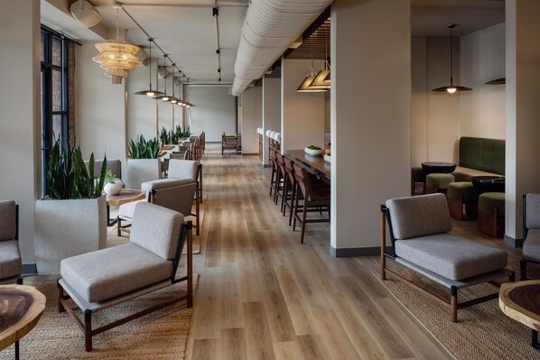 A modern office space with a long dining table, multiple chairs, and hanging pendant lights.