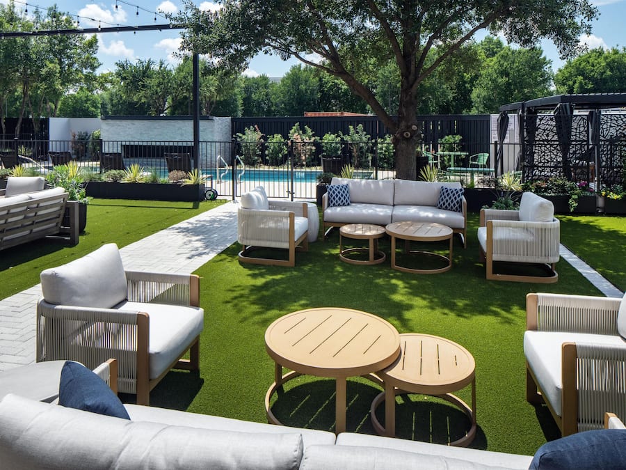 A patio with outdoor furniture, a pool, and a garden area.