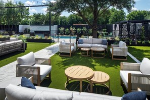 Un patio con mobiliario exterior, una piscina y un jardín.