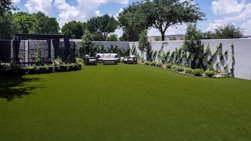 Un césped bien cuidado con una zona de estar y una valla decorativa.