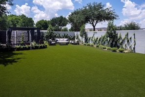 A well-maintained lawn with a seating area and a decorative fence. - The Clara Hotel Plano Tapestry Collection by Hilton (Plano)