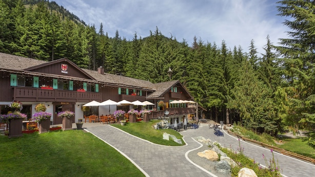 A lodge with outdoor seating and a mountain backdrop. - Crystal Mountain Hotels (Enumclaw)