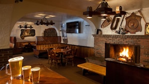 A cozy pub with a brick fireplace, wooden furniture, and a variety of mounted items on the walls. - Crystal Mountain Hotels (Enumclaw)