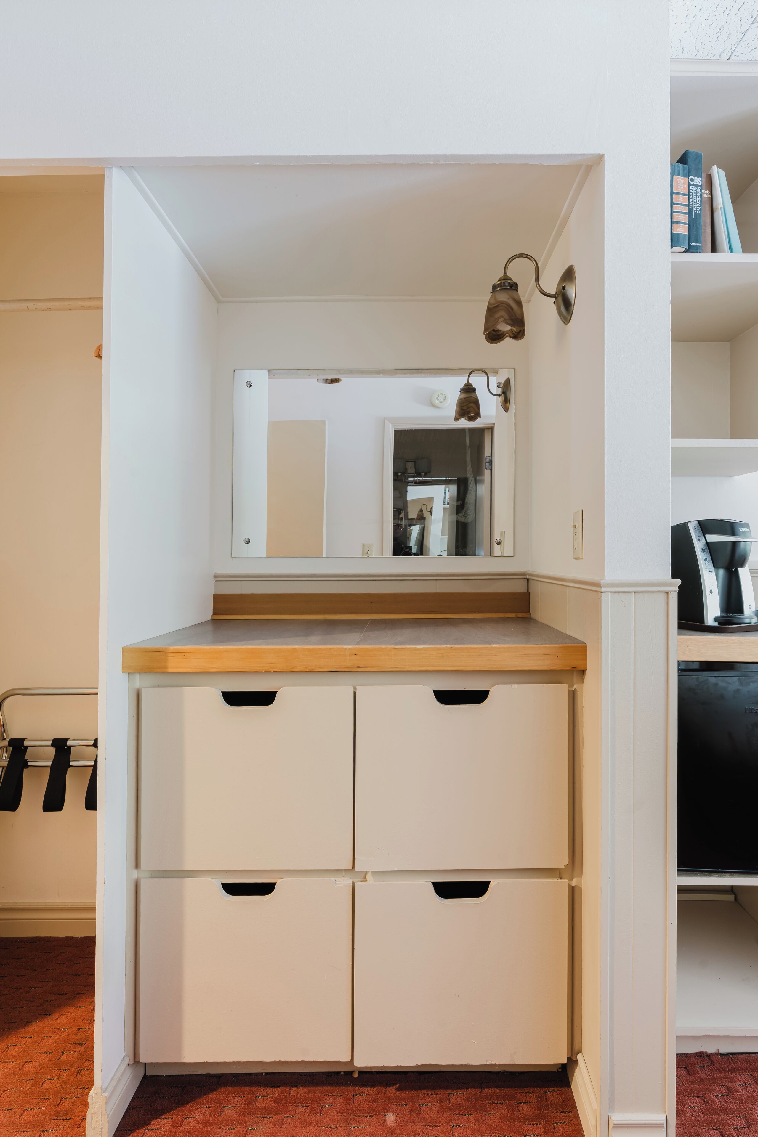Une armoire blanche avec un miroir, un plan de travail en bois et deux tiroirs.