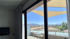 Une chambre dotée d’une grande fenêtre donnant sur une piscine et des montagnes.