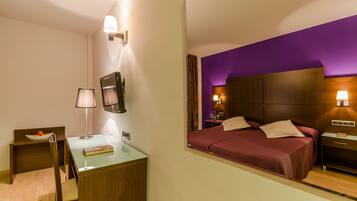 A hotel room with a bed, bedside tables, a desk, and a chair.