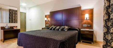 A modern bedroom with a large bed, wooden headboard, bedside tables, and a nightstand.