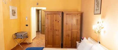A hotel room with a bed, a wardrobe, a chandelier, and a suitcase.