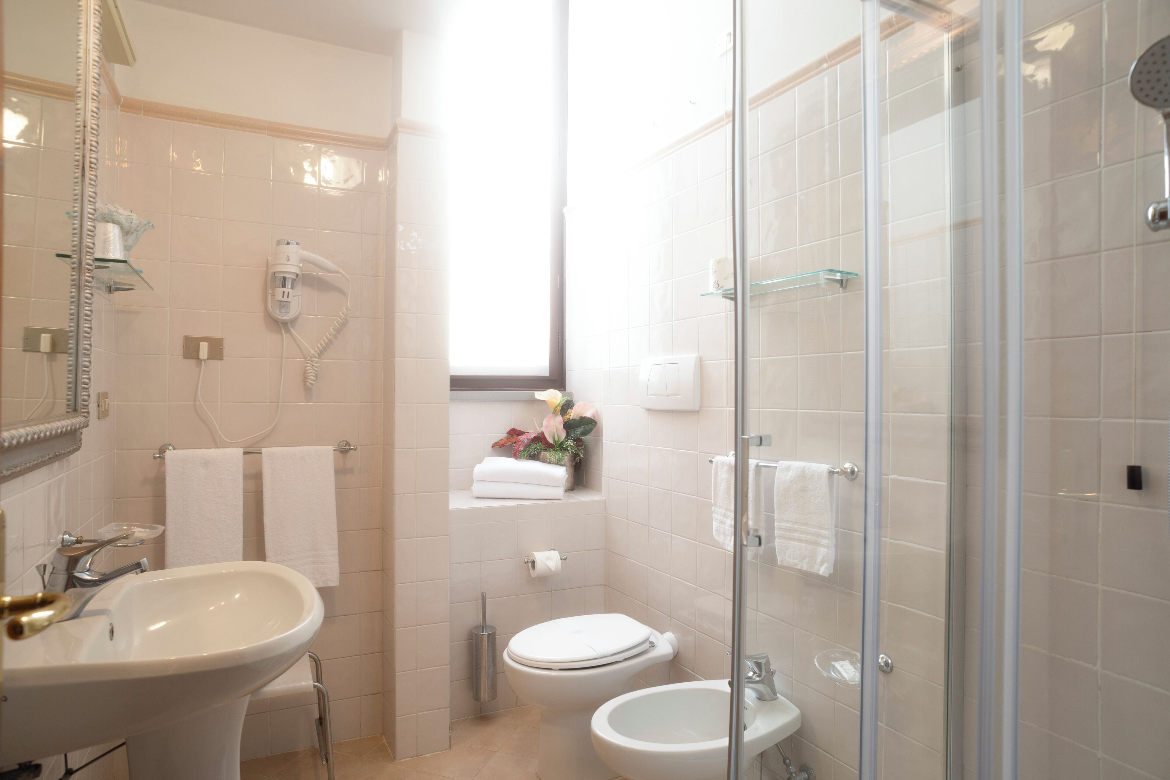 A bathroom with a sink, toilet, bidet, and glass-enclosed shower.