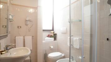 A bathroom with a sink, toilet, bidet, and glass-enclosed shower.
