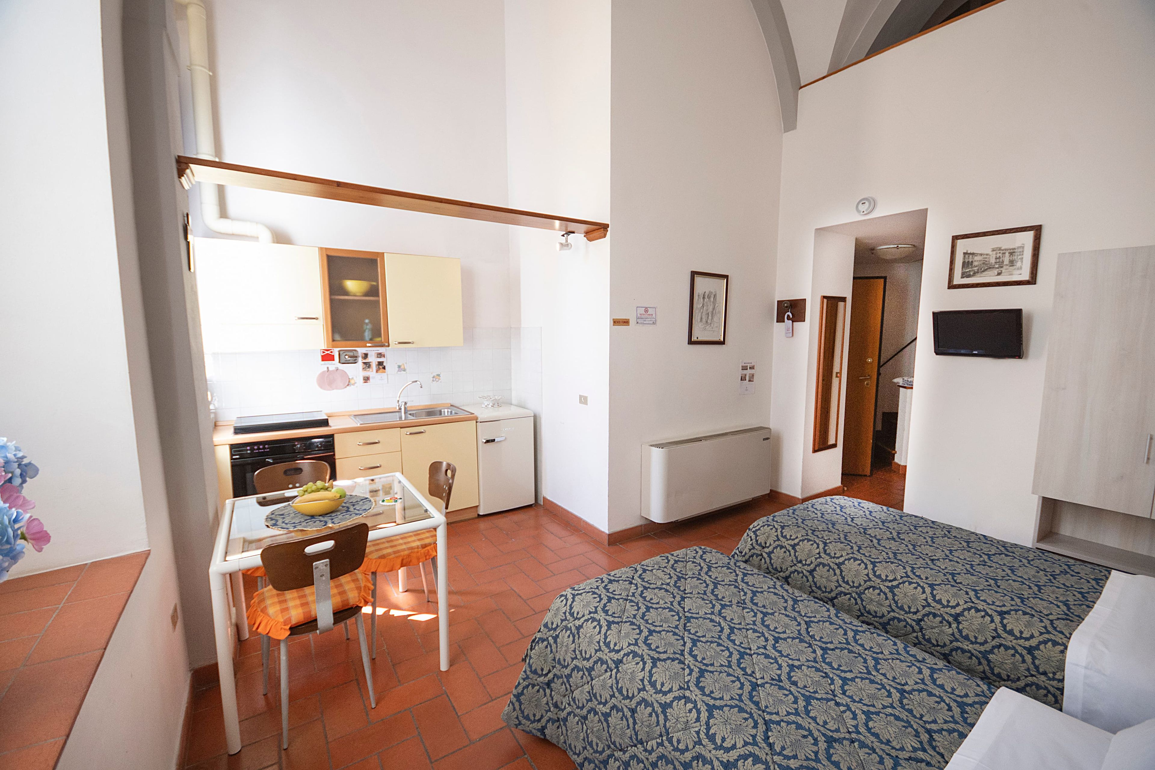 Un espace de vie compact comprenant un coin cuisine, un espace repas et une chambre.