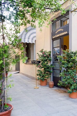 Un edificio con un letrero que dice 'Residence La Contessina' y un camino bordeado de plantas en macetas.