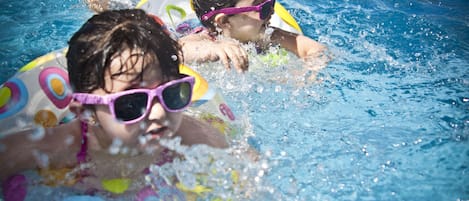 Dos personas nadando en una piscina con flotadores.