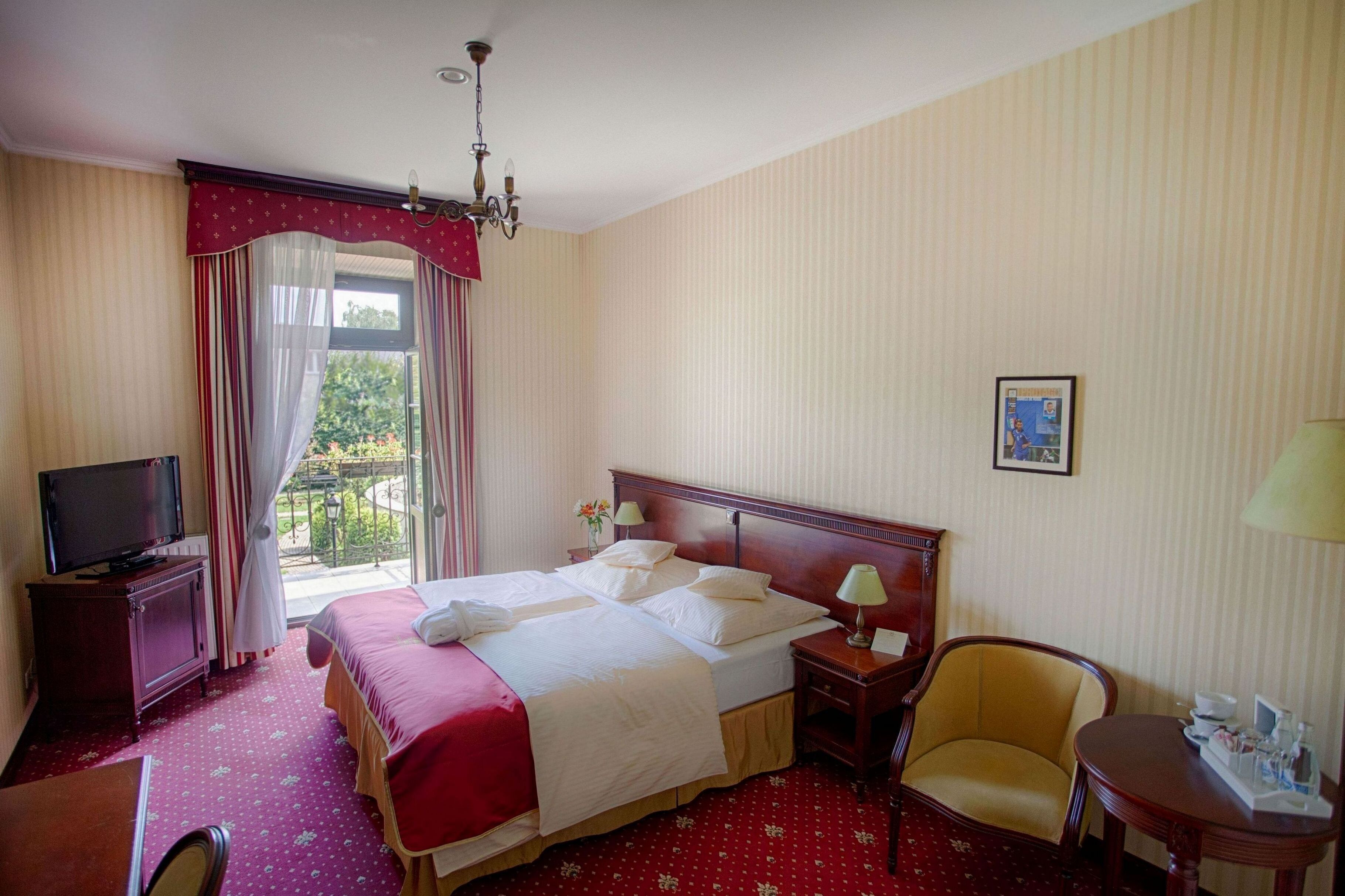 Une chambre d’hôtel avec un grand lit, une télévision, un bureau et une chaise.