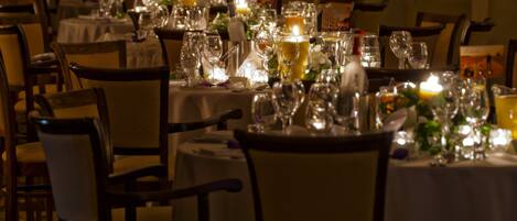 A restaurant setting with round tables, chairs, and various dining utensils.