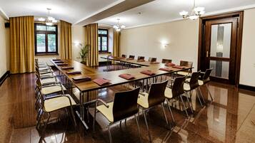 Une salle de conférence avec une longue table, des chaises et un lustre.