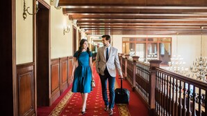 A corridor with wooden paneling and a red carpet, leading to a balcony with a railing and chandeliers. - Turowka Hotel & Spa (Wieliczka)