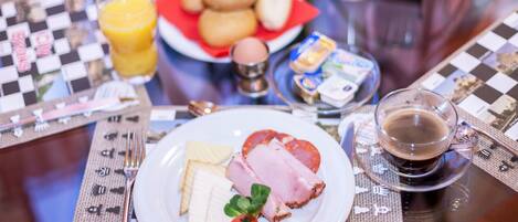 Desayuno con un plato de comida, un vaso de jugo de naranja y una taza de café sobre un mantel a cuadros.