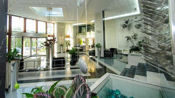 A modern hotel lobby with a reception desk, seating area, and a staircase with glass railings. - Continental Forum Sibiu (Sibiu)