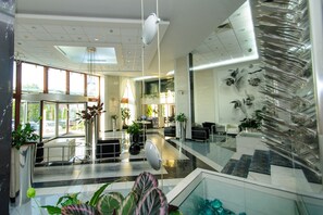 A modern hotel lobby with a reception desk, seating area, and a staircase with glass railings. - Continental Forum Sibiu (Sibiu)