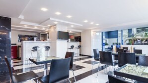 A modern hotel lobby with a check-in counter, seating area, and a large window with a view of palm trees. - Continental Forum Sibiu (Sibiu)