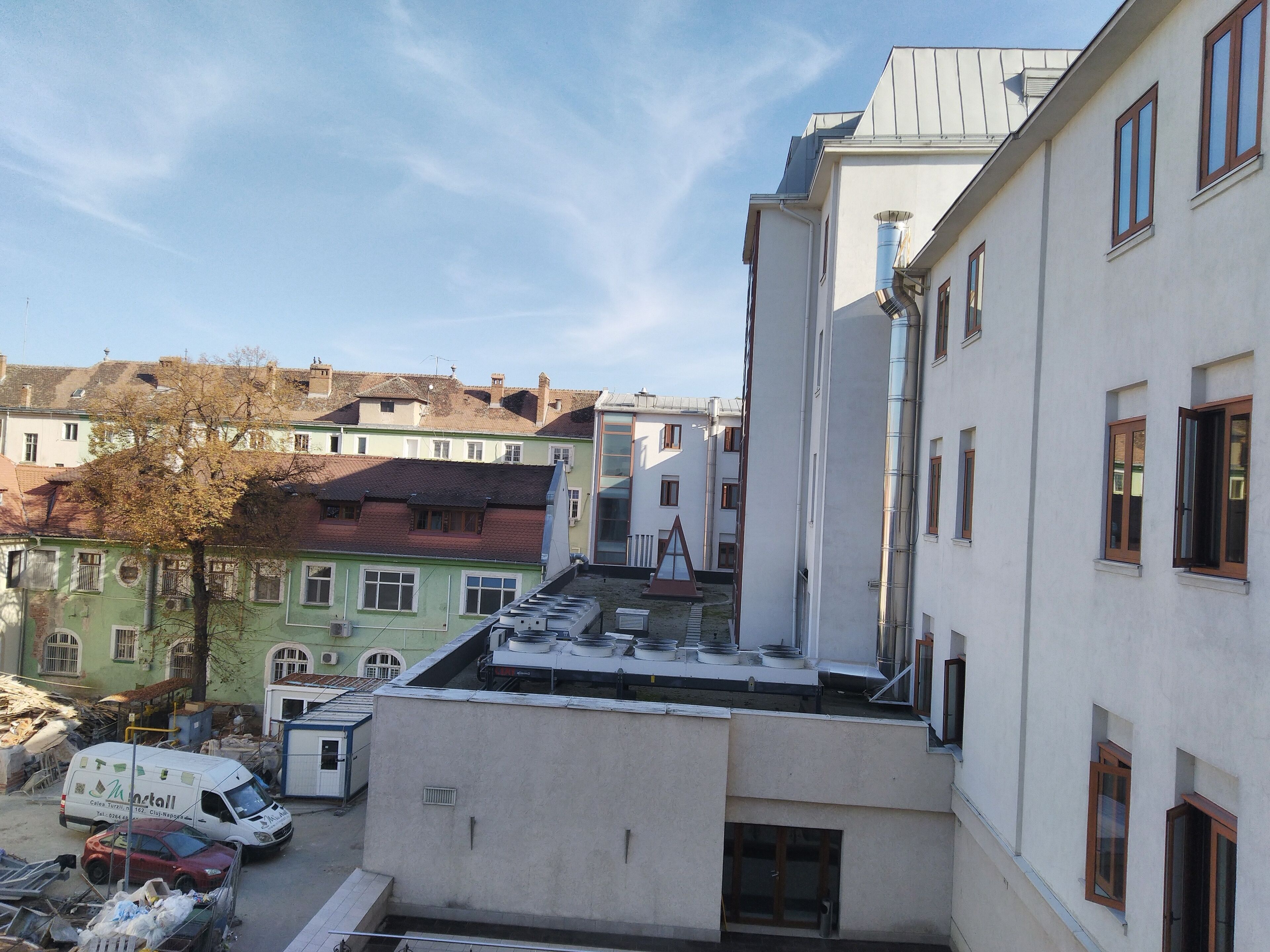 A multi-story building with a flat roof, large windows, and a visible chimney.