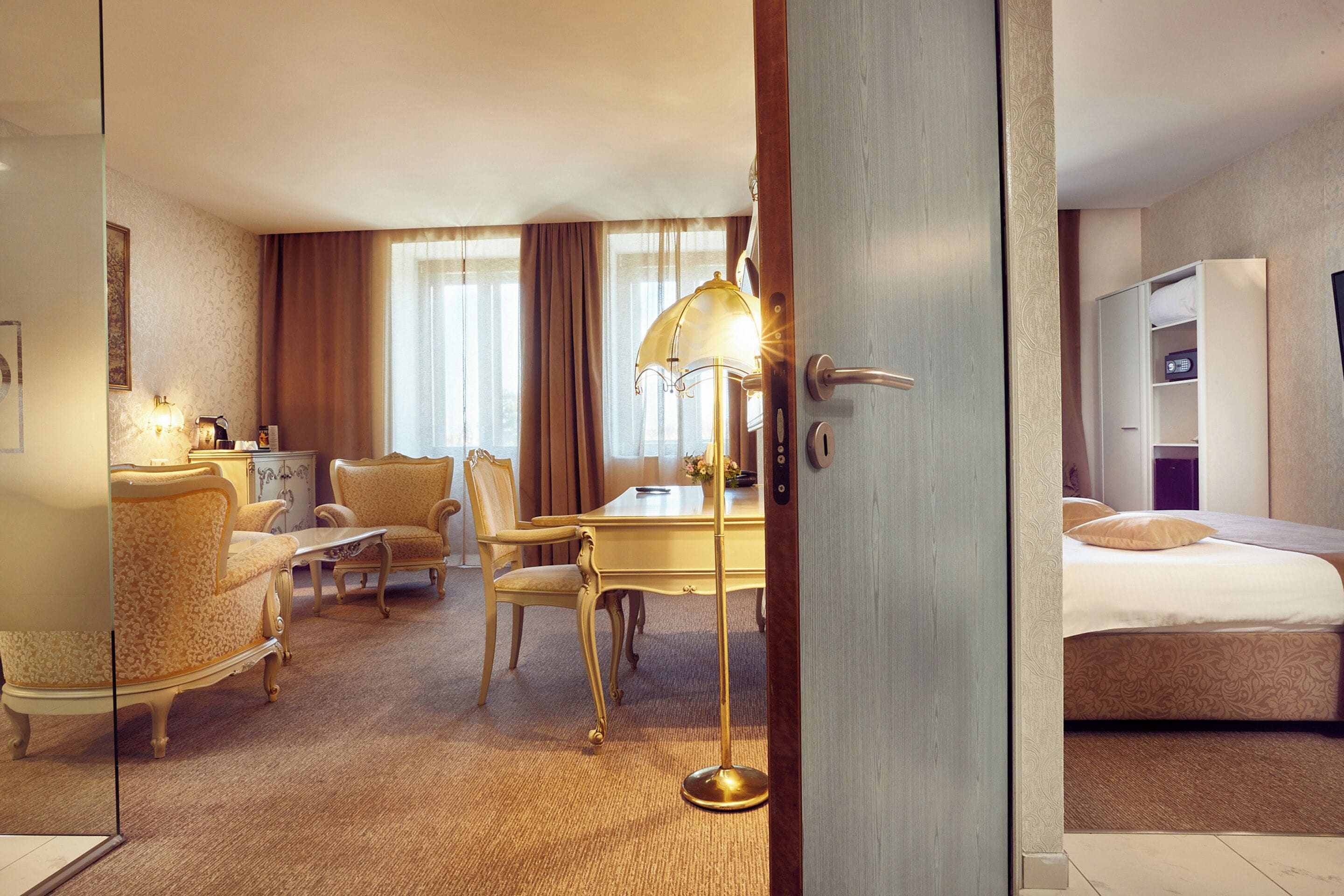 Ein Hotelzimmer mit Bett, Schreibtisch, zwei Stühlen, einer Lampe und einem Kleiderschrank.