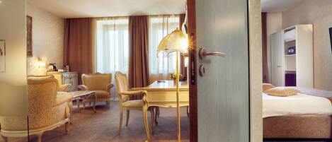 Ein Hotelzimmer mit Bett, Schreibtisch, zwei Stühlen, einer Lampe und einem Kleiderschrank.