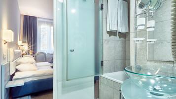 Una moderna camera d'albergo con box doccia in vetro, lavabo in vetro e un letto con vista sull'esterno.
