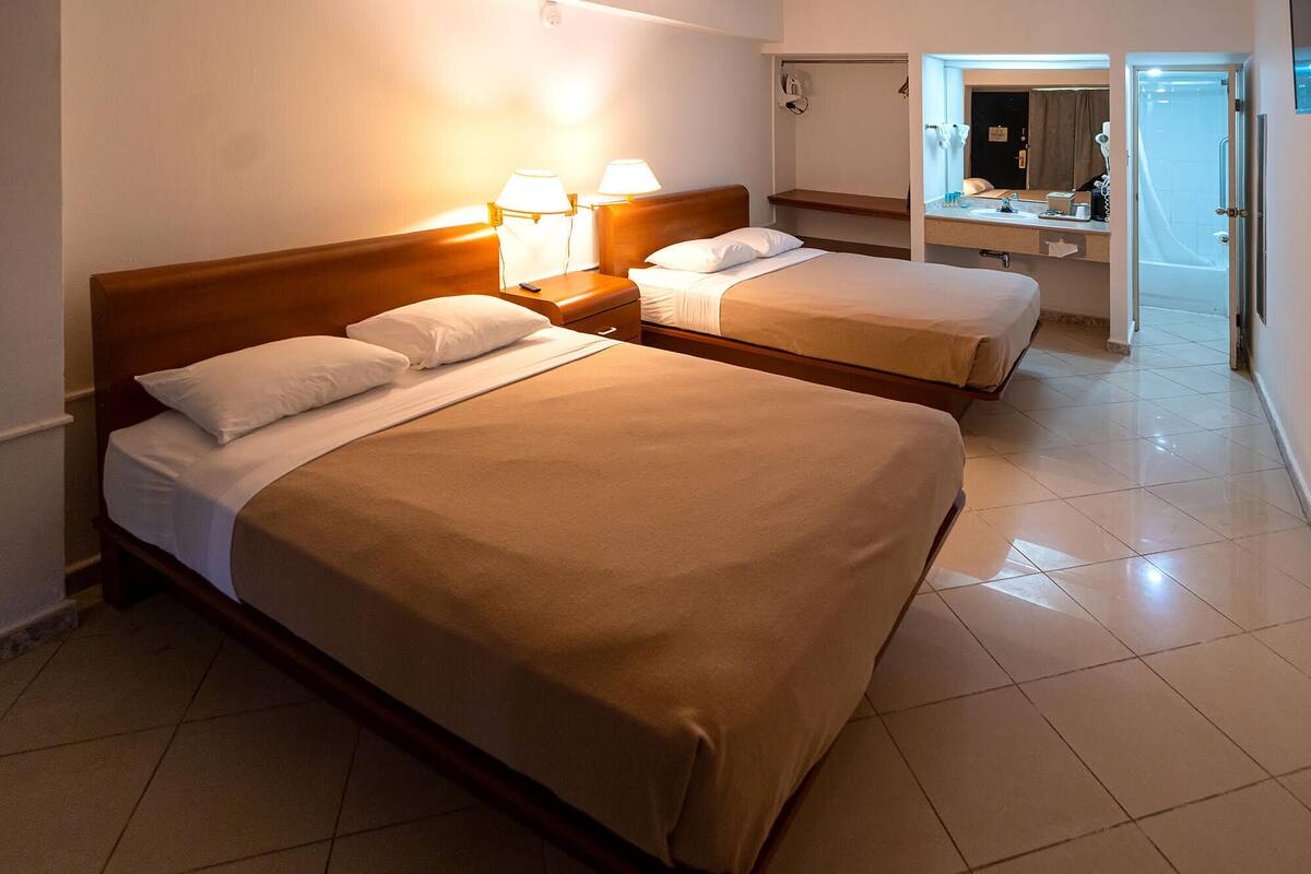 Une chambre d’hôtel avec deux lits, une salle de bain et un miroir.