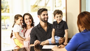 Una familia sentada en una mesa en una habitación con ventanas amplias y vistas al exterior.