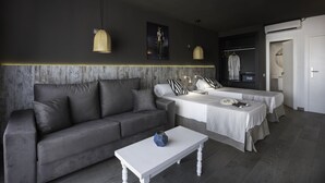 A modern hotel room with a grey sofa, a white coffee table, a bed with a white bedspread, and a wardrobe. - Aparthotel Vibra Mogambo - Adults Only (Sant Josep de sa Talaia)