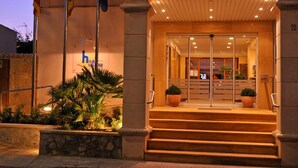 Entrada d'hotel amb una porta de vidre, escales i plantes en testos.