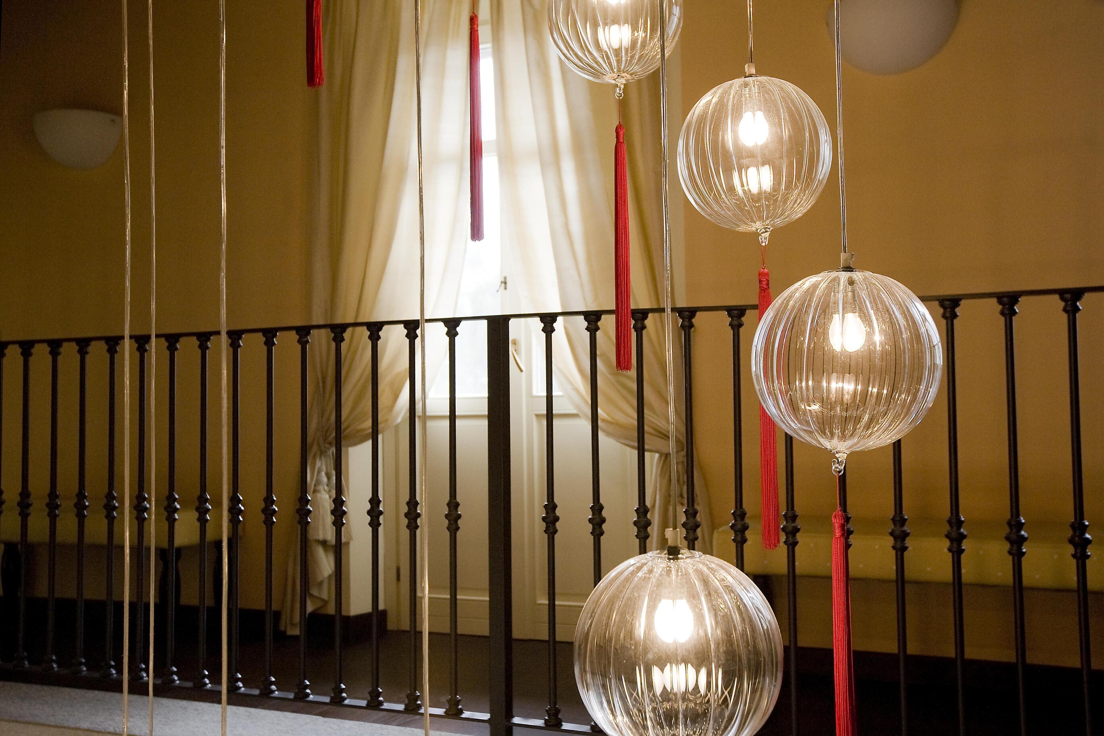 A staircase with a black balustrade and clear glass pendant lights with red tassels.
