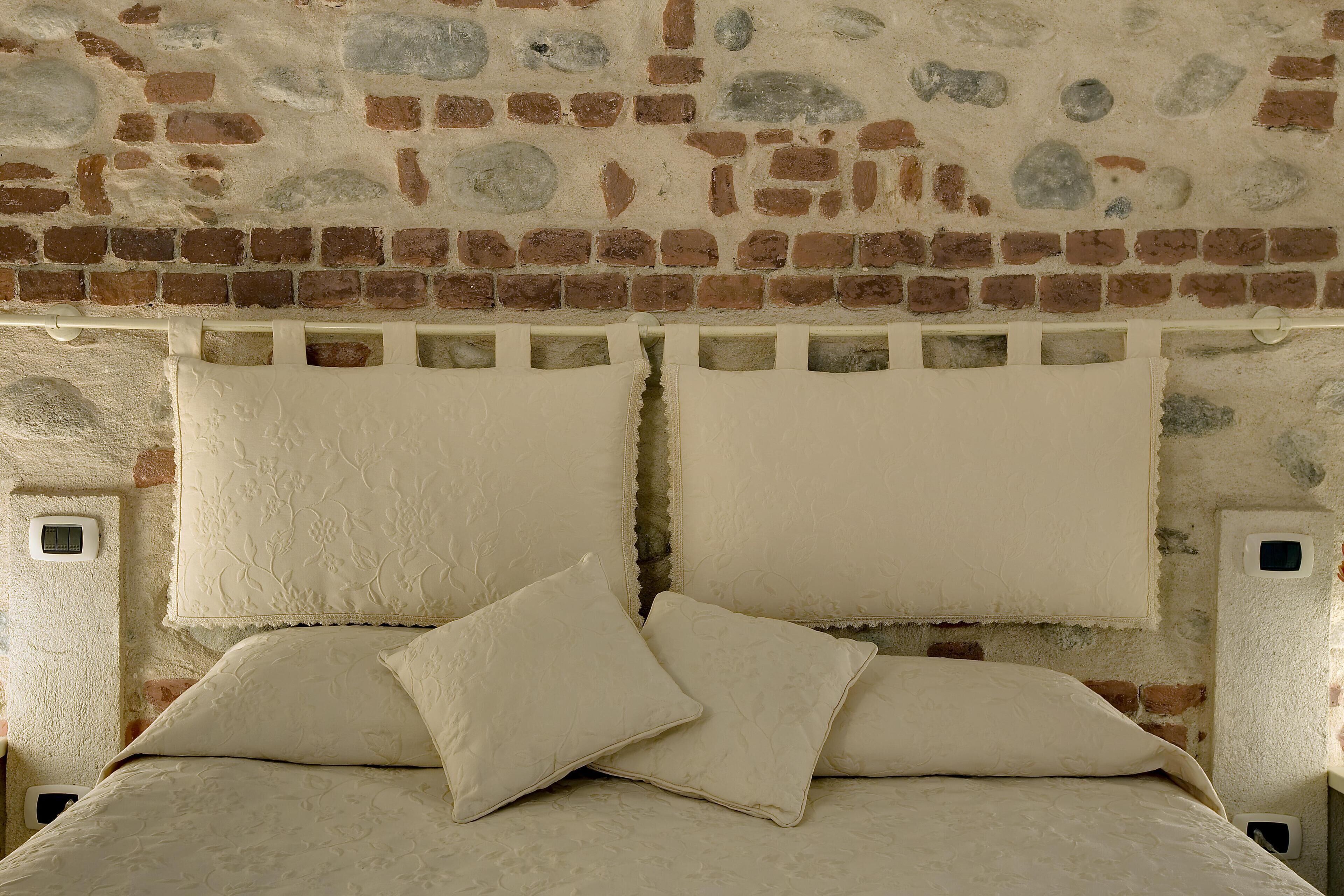 Una cama con cabecera de ladrillo y dos almohadas.